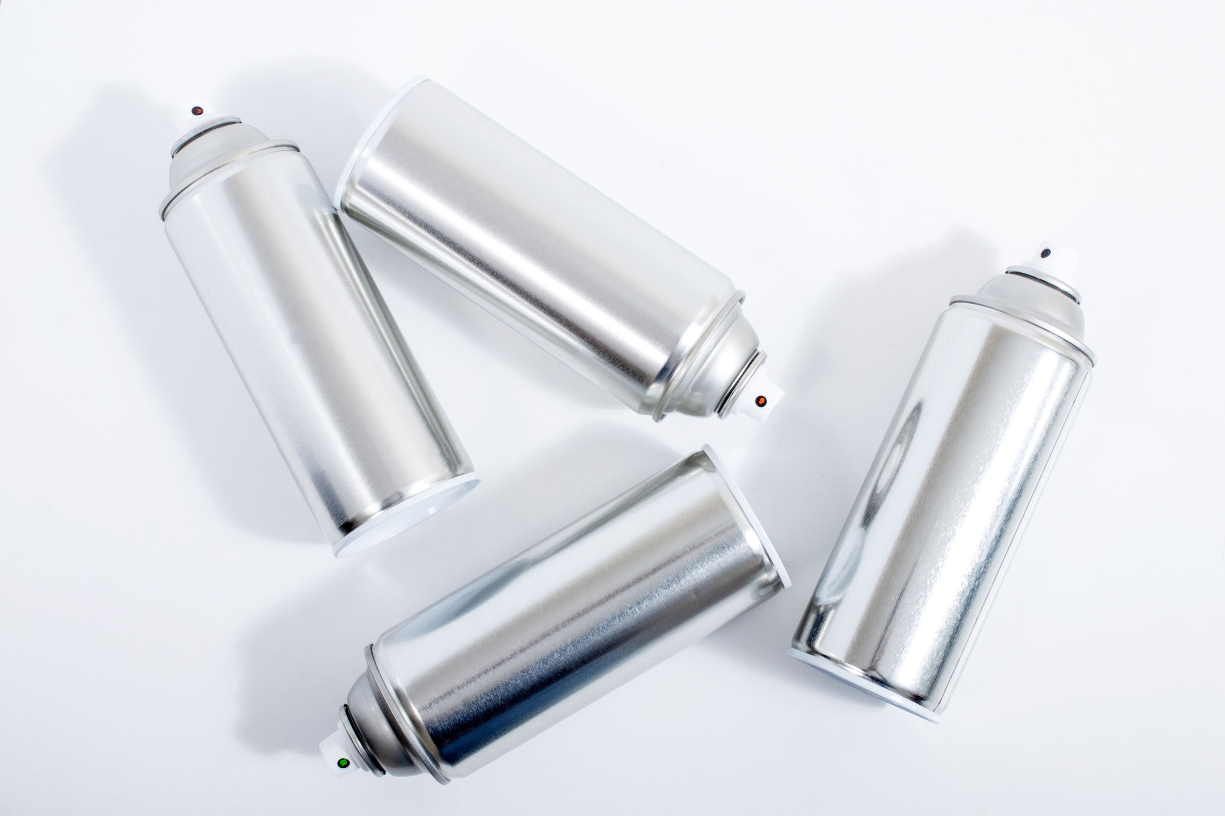 Close up view of silver spray cans on a white background.